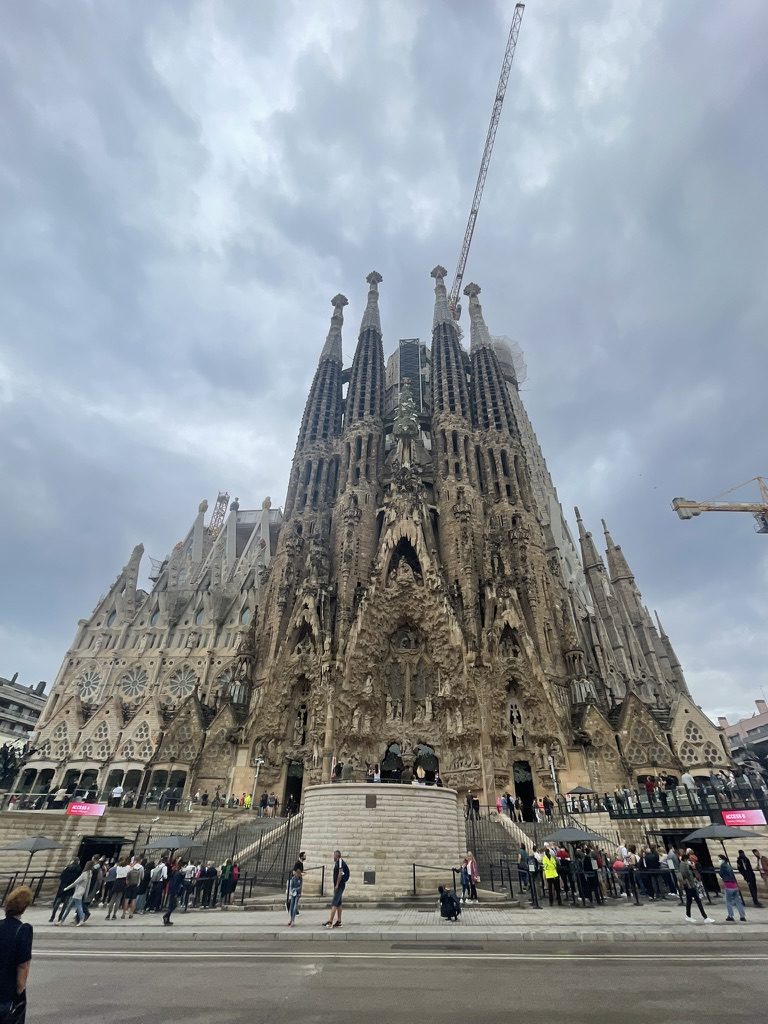 The Sagrada Família under a grey sky with a crane on top