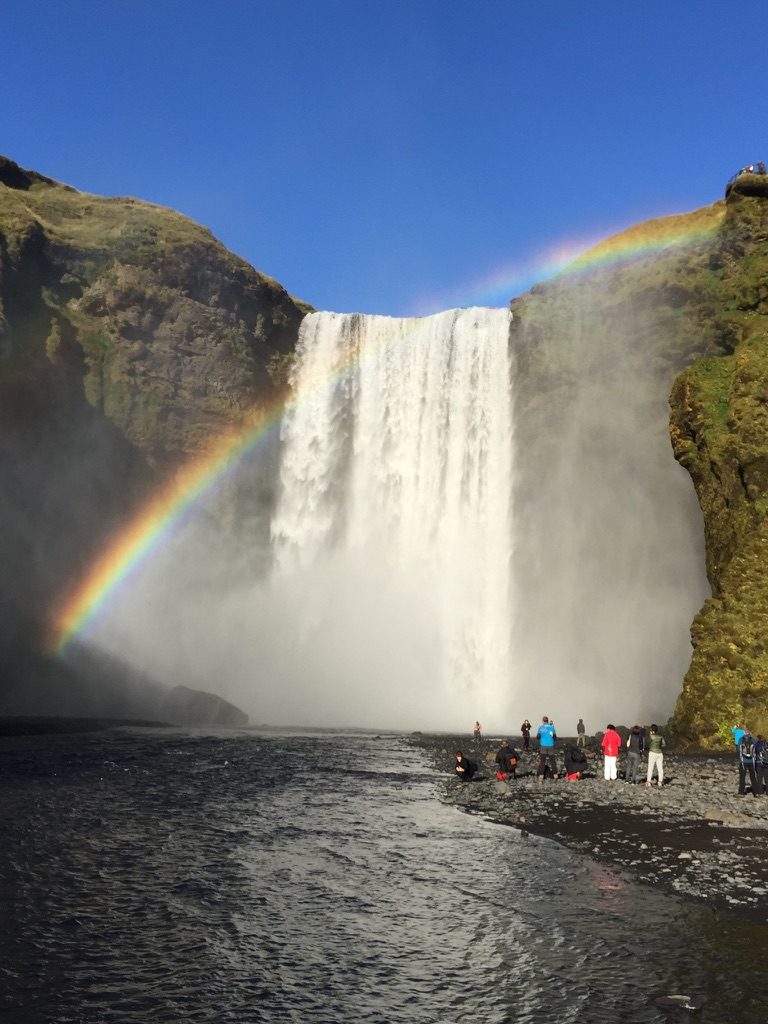 A rainbow arcing across the base of Skógafoss waterfall