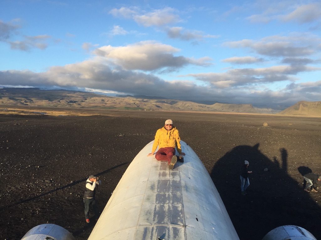Sitting on top of a crashed DC-3 wreck on black sand in evening light