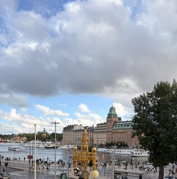 A waterfront promenade in Stockholm with boats and a green-roofed building